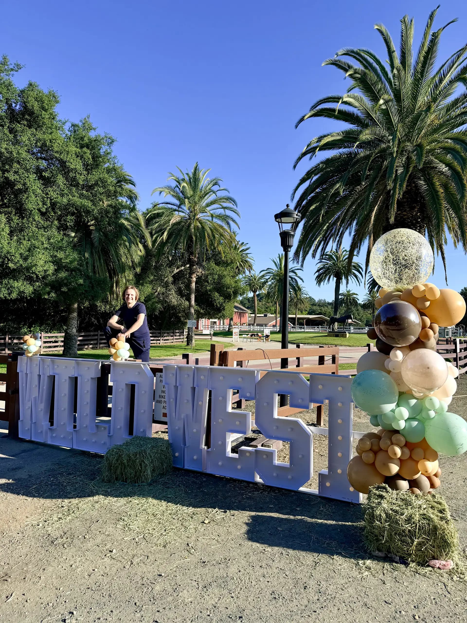 Freestanding Wild West letters and organic balloon columns installed on site for the Wild West Alumni Spring Party in San Francisco Bay Area, California, frame 5 of 8.